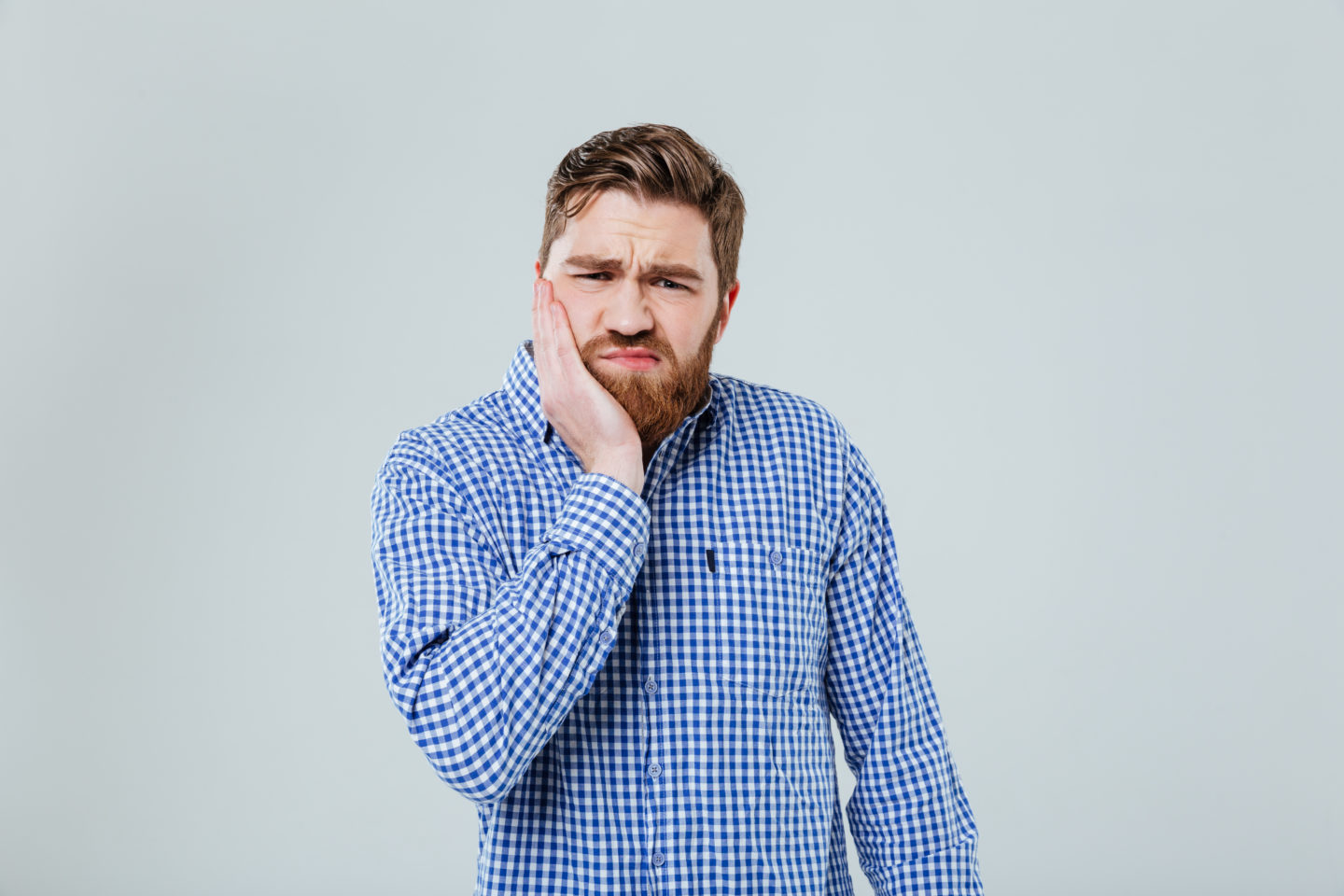 Sad bearded young man standing and having toothache