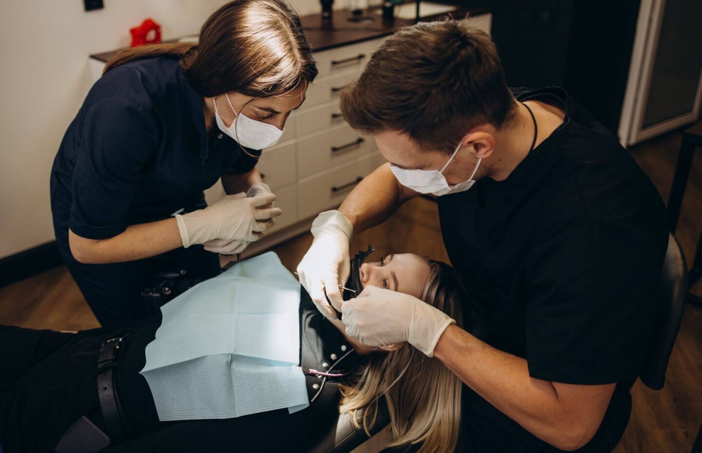 A dentist and an assistant working on a patient's teeth in a dental office.