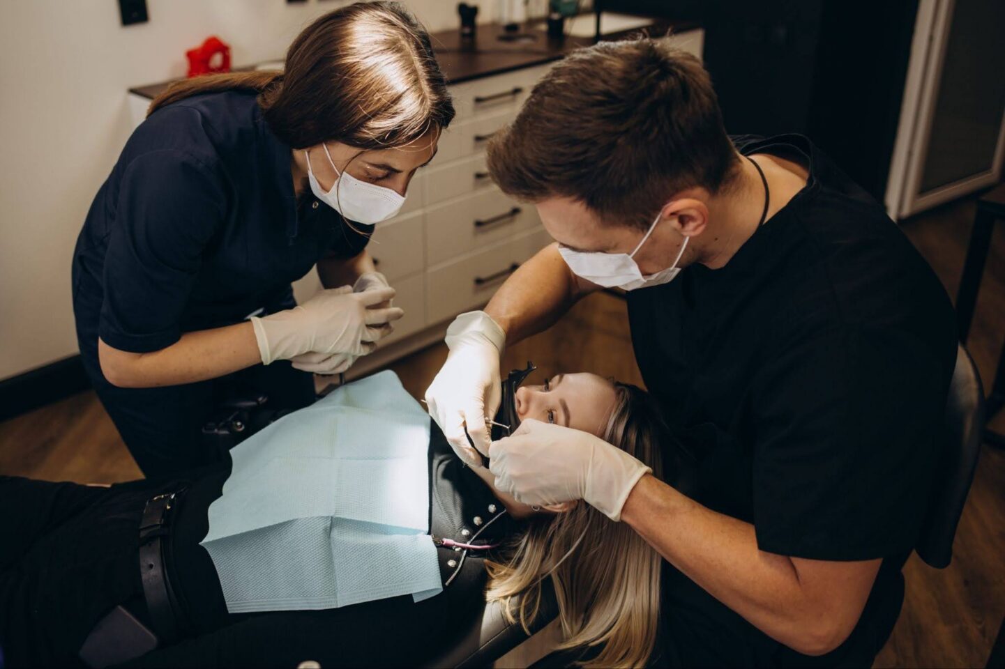 A dentist and an assistant working on a patient's teeth in a dental office.