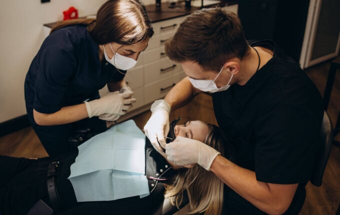 A dentist and an assistant working on a patient's teeth in a dental office.